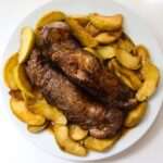 Apple and pork tenderloin with cooked apple slices and maple Dijon sauce on a serving platter.