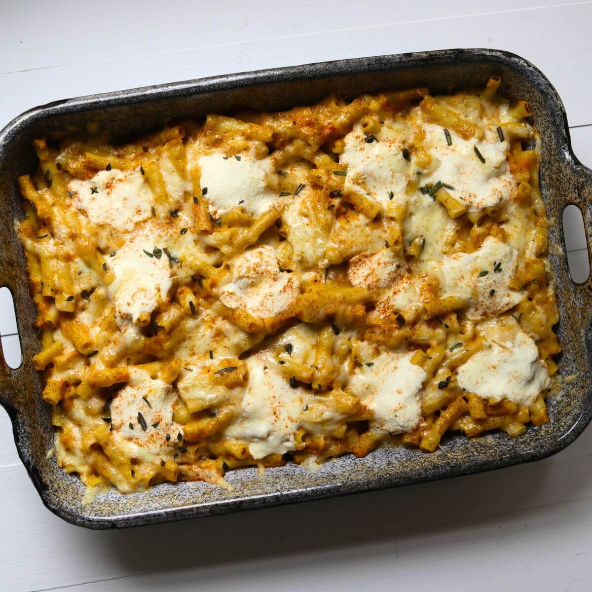 Baked pumpkin pasta with ziti, melted cheese, ricotta, fresh herbs, and smoked paprika.