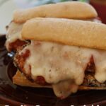 Eggplant Parmesan sandwich with crispy breaded eggplant, marinara sauce, and melted Monterey Jack cheese on a toasted baguette. Text overlay reads "Eggplant Parmesan Sandwich".