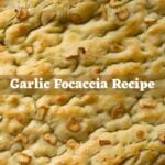 Garlic focaccia bread topped with sliced garlic and text overlay reading “Garlic Focaccia Recipe".