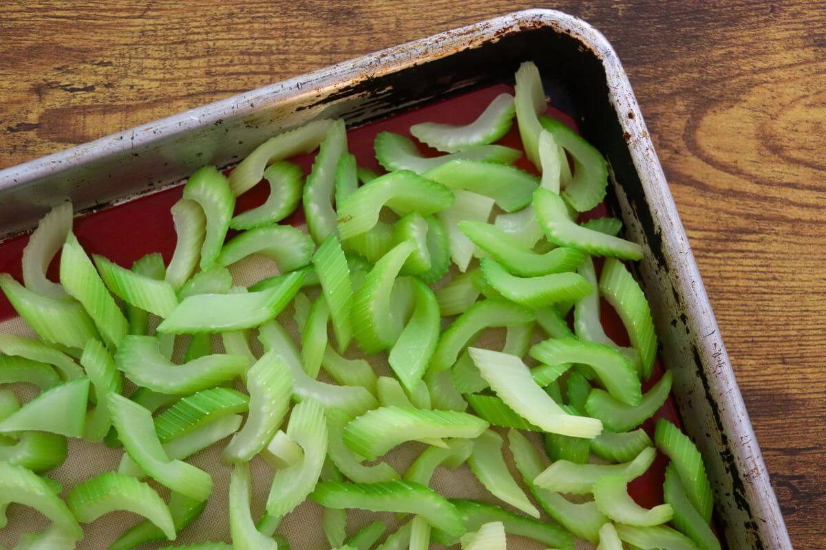 Fresh celery slices arranged on a baking sheet for flash freezing.