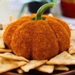 Pumpkin-shaped cheese ball coated in orange seasoning with a green stem, crackers, and “Pumpkin Cheese Ball Recipe” text.