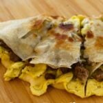Sausage, egg, and cheese quesadilla with golden tortilla and text reading “Sausage Egg & Cheese Quesadilla".