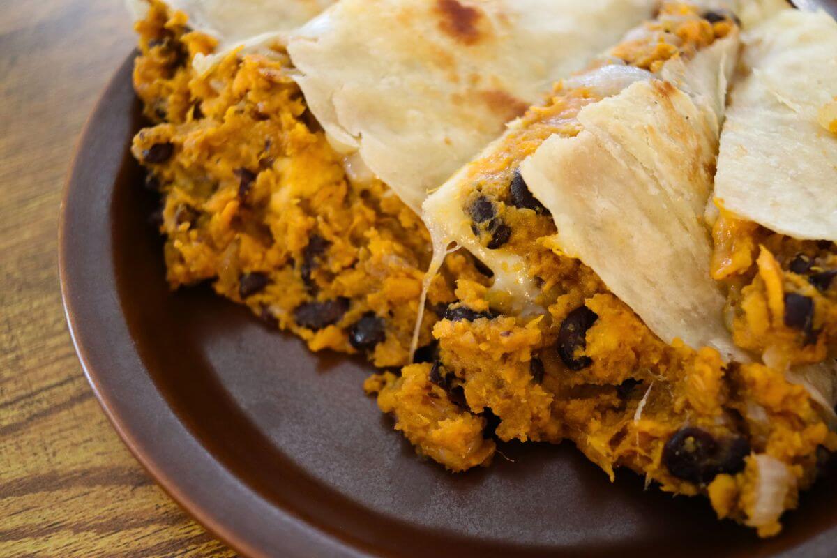 Sweet potato quesadilla cut into wedges with black beans, onion, and melted Monterey Jack cheese.