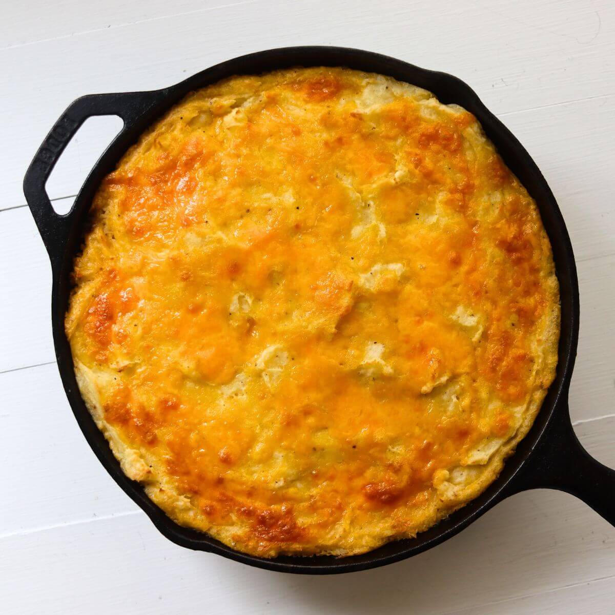 Traditional cottage pie baked in a cast iron skillet with a golden cheddar potato topping.