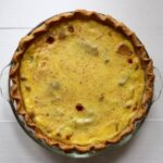Apple custard pie with a golden crust, creamy custard filling, and visible pieces of apple.