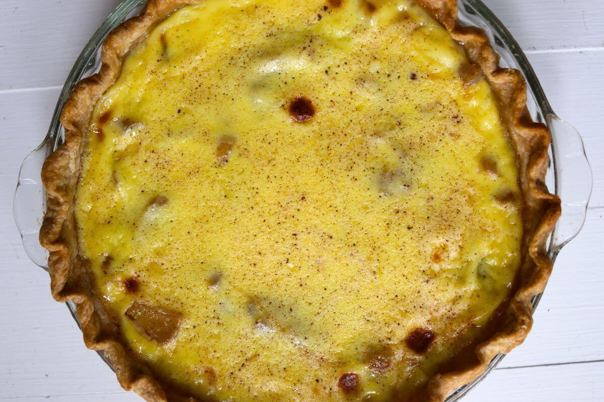 Homemade apple custard pie with baked apples in creamy custard and a golden, flaky pie crust.