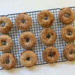 Baked apple cider donuts with cinnamon sugar coating cooling on a wire rack.