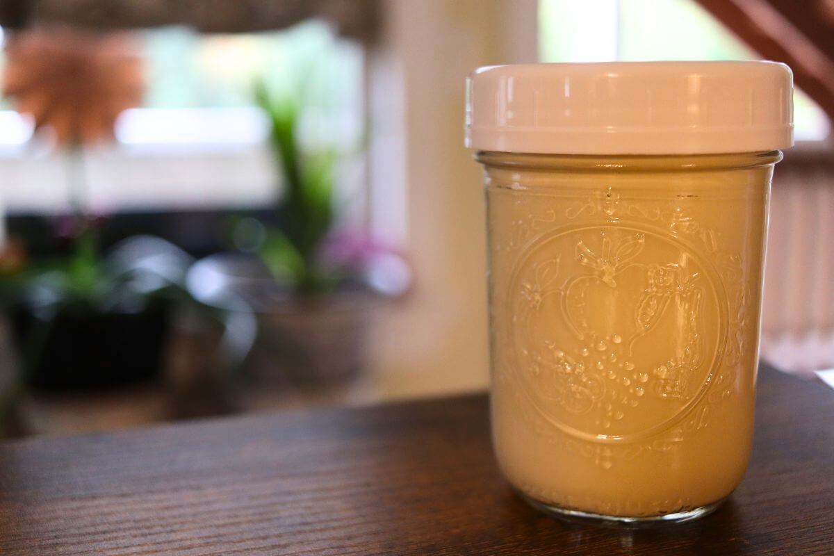 Glass jar filled with creamy brown sugar creamer in a softly lit kitchen.