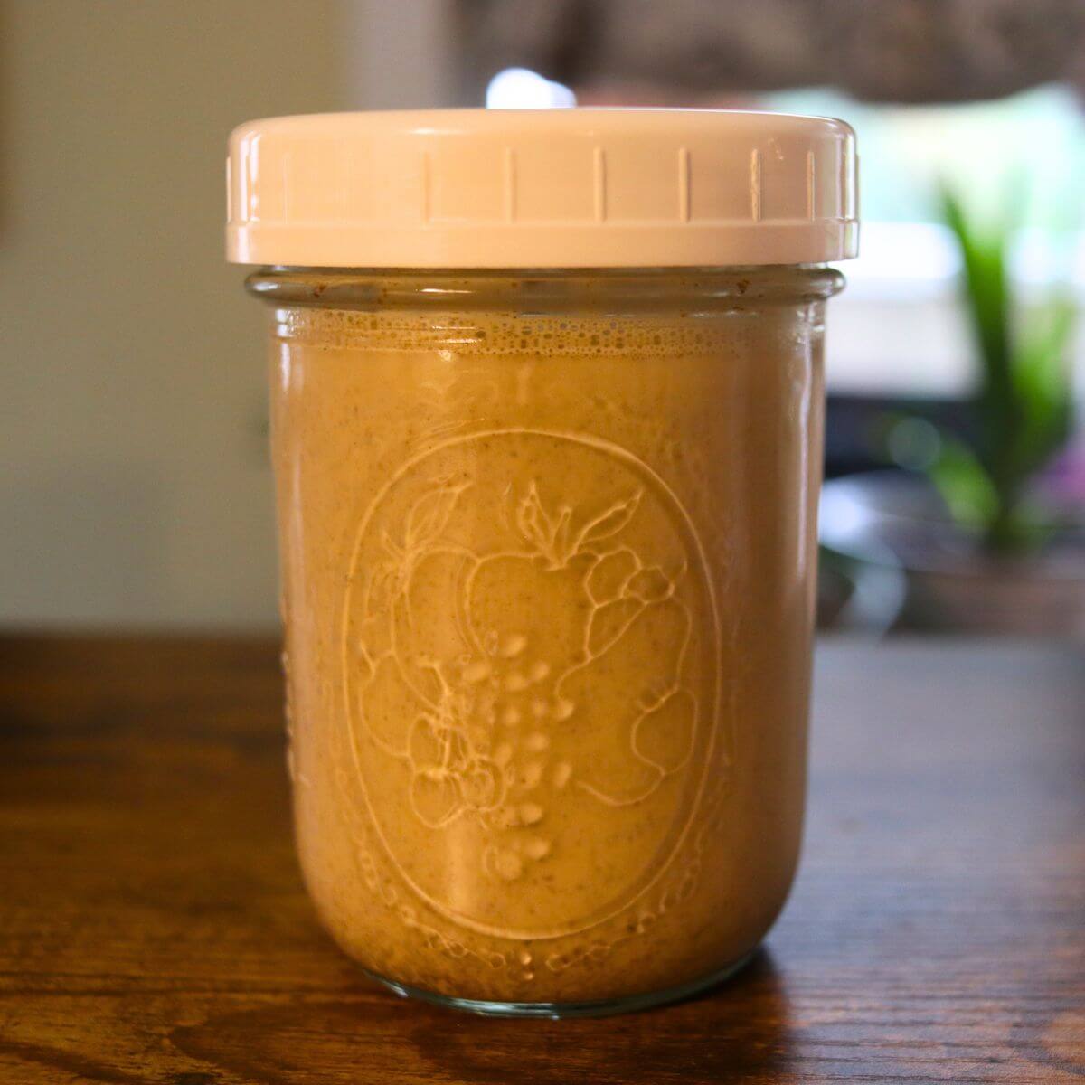 Homemade cinnamon roll coffee creamer in a covered glass jar.