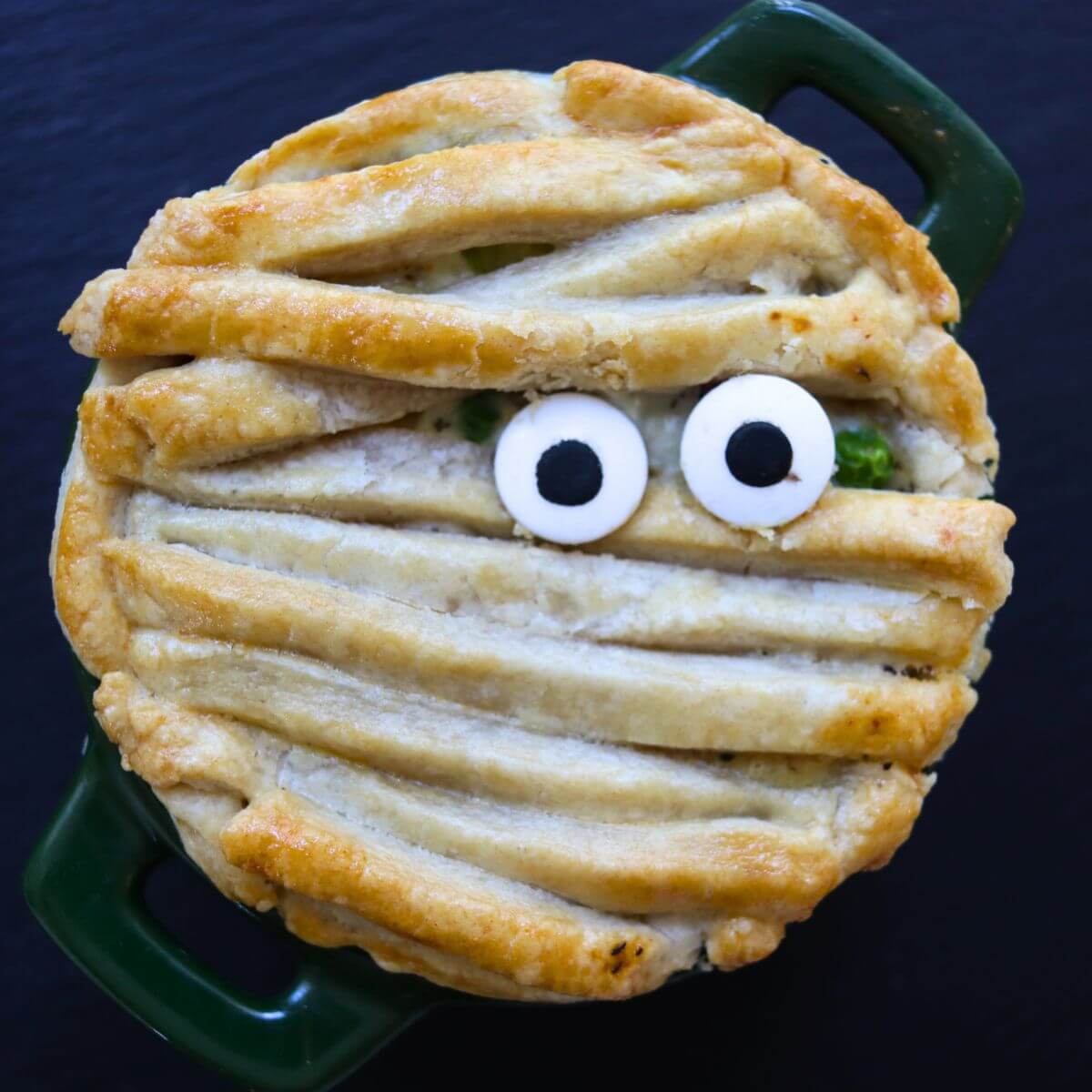 Halloween chicken pot pie topped with mummy-style pie crust strips and candy eyes.