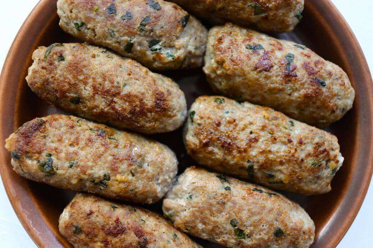 Homemade garlic basil sausage links with visible flecks of fresh basil and golden brown surfaces.