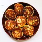 Crispy mashed potato patties with browned edges and visible pieces of green scallion.