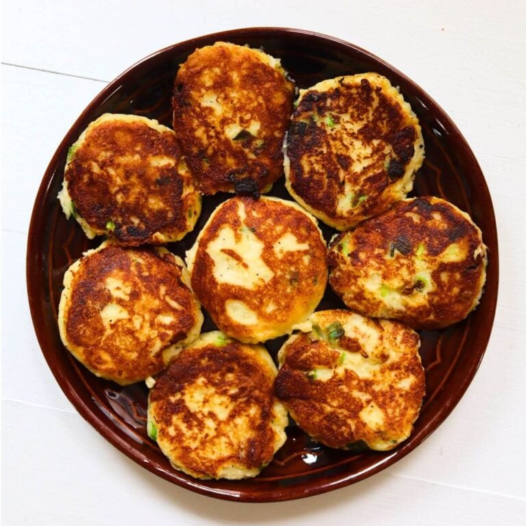 Crispy mashed potato patties with browned edges and visible pieces of green scallion.