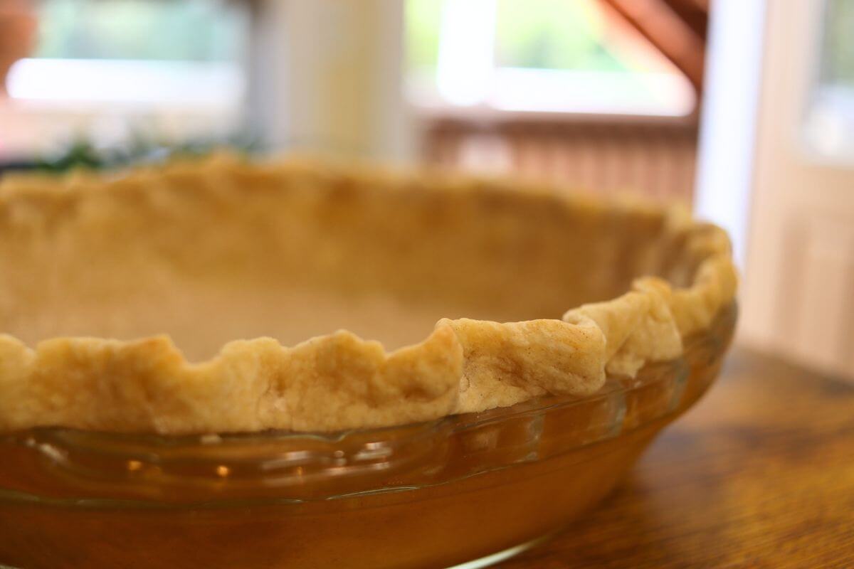 Pie crust from scratch with crimped edges in a clear glass pie dish.