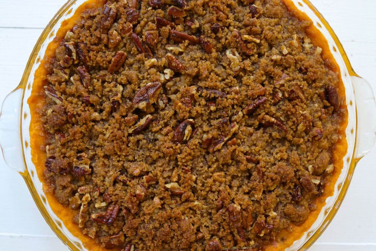 Sweet potato casserole with a golden brown sugar pecan topping baked in a glass pie dish.