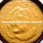 Homemade apple cider mustard with a thick, golden texture in a brown bowl, featuring the text “Homemade Apple Cider Mustard".