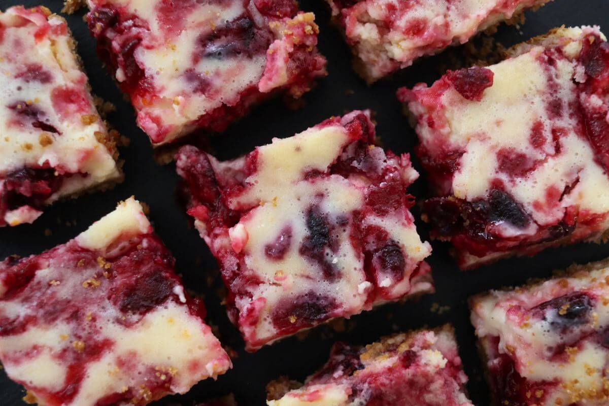 Cranberry cheesecake bars with creamy cheesecake filling, red cranberry swirls, and golden graham cracker crust.