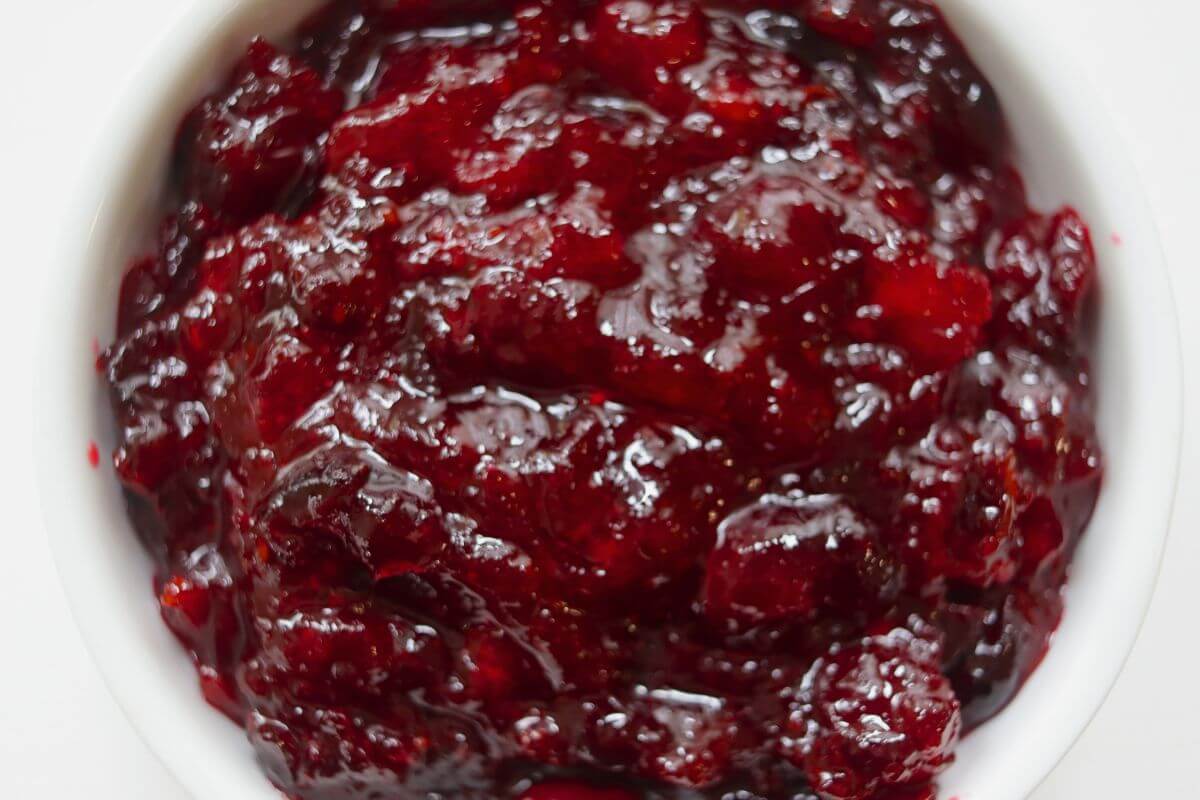 Cranberry compote with softened berries and a rich red sauce served in a white bowl.