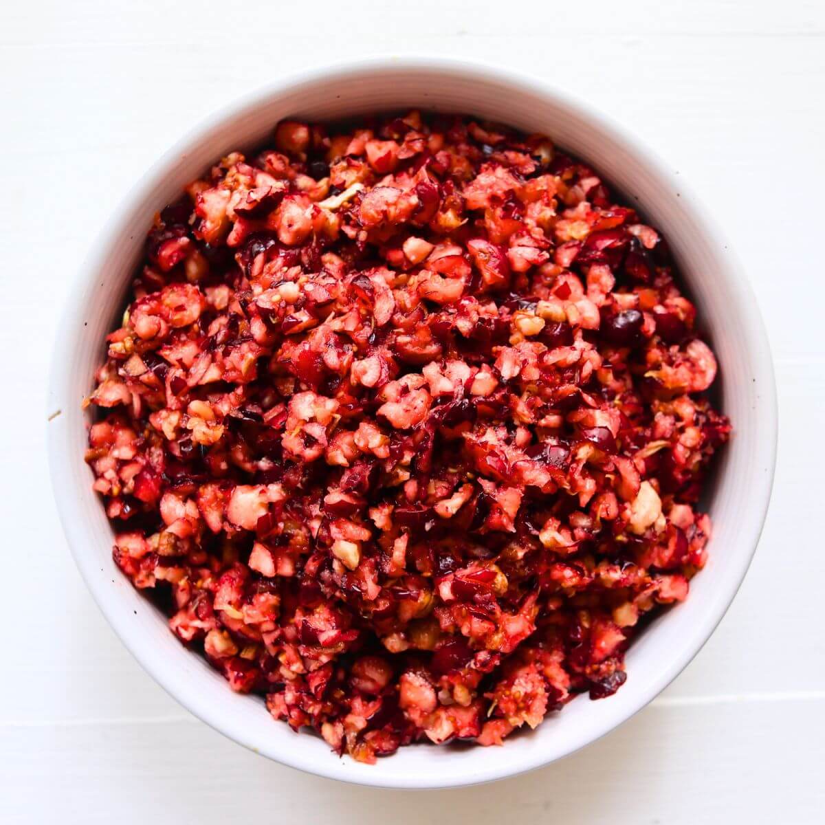 Cranberry orange relish with finely chopped cranberries and pecans in a white serving bowl.
