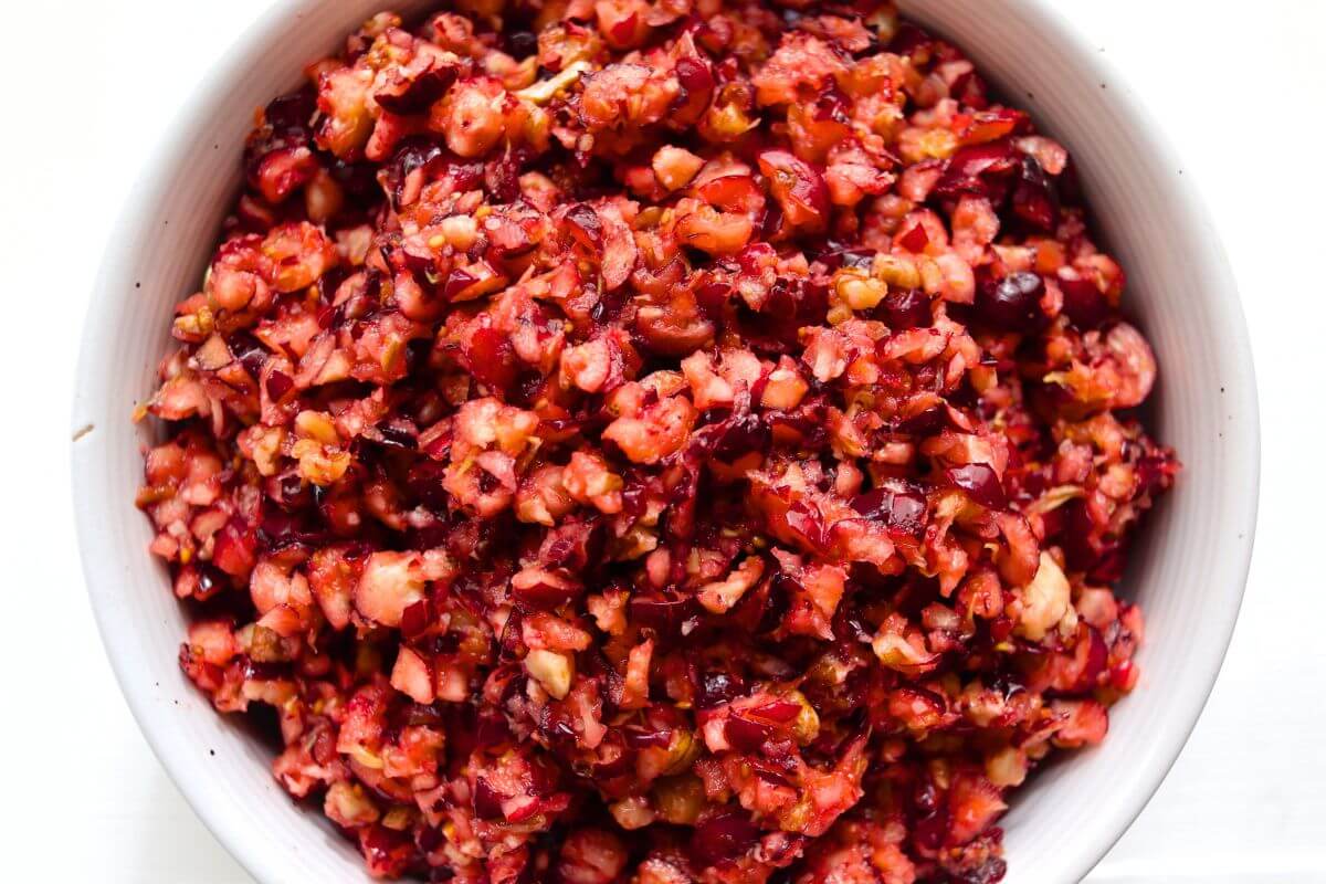Cranberry orange relish with a chunky texture, vibrant red cranberries, and pieces of chopped pecans.