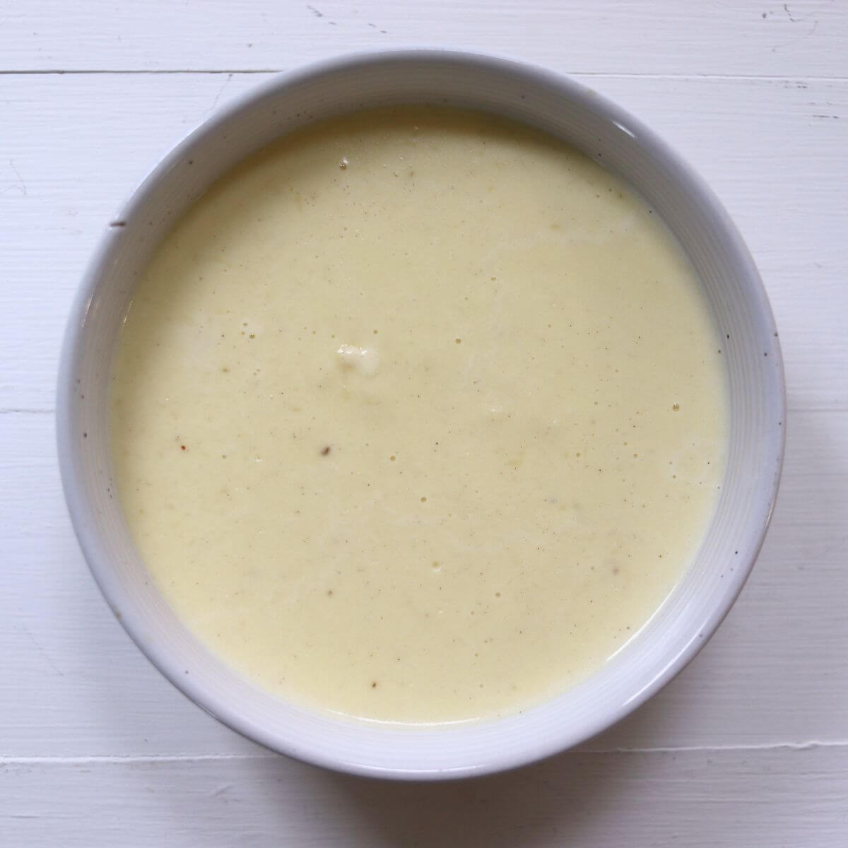 Easy homemade Alfredo sauce with a smooth texture in a ceramic bowl.