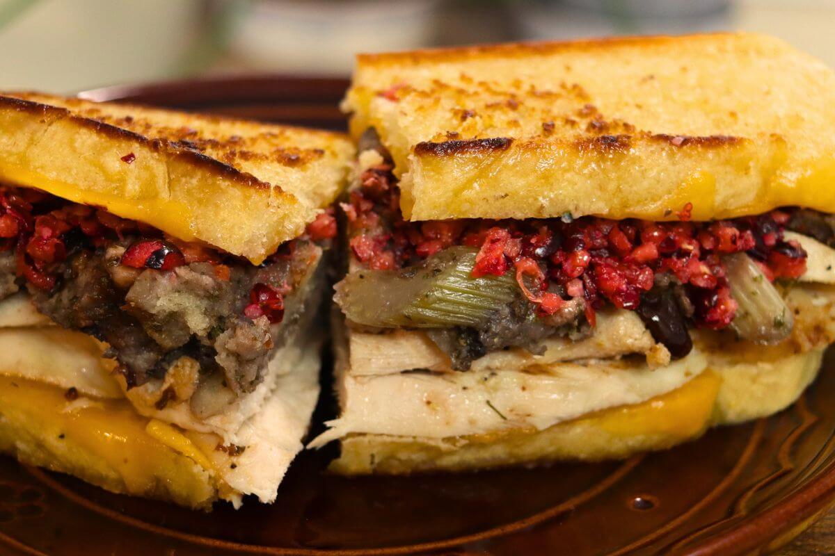 Grilled leftover turkey sandwich filled with sliced turkey, stuffing, cranberry relish, and melted cheddar cheese on golden toasted bread.