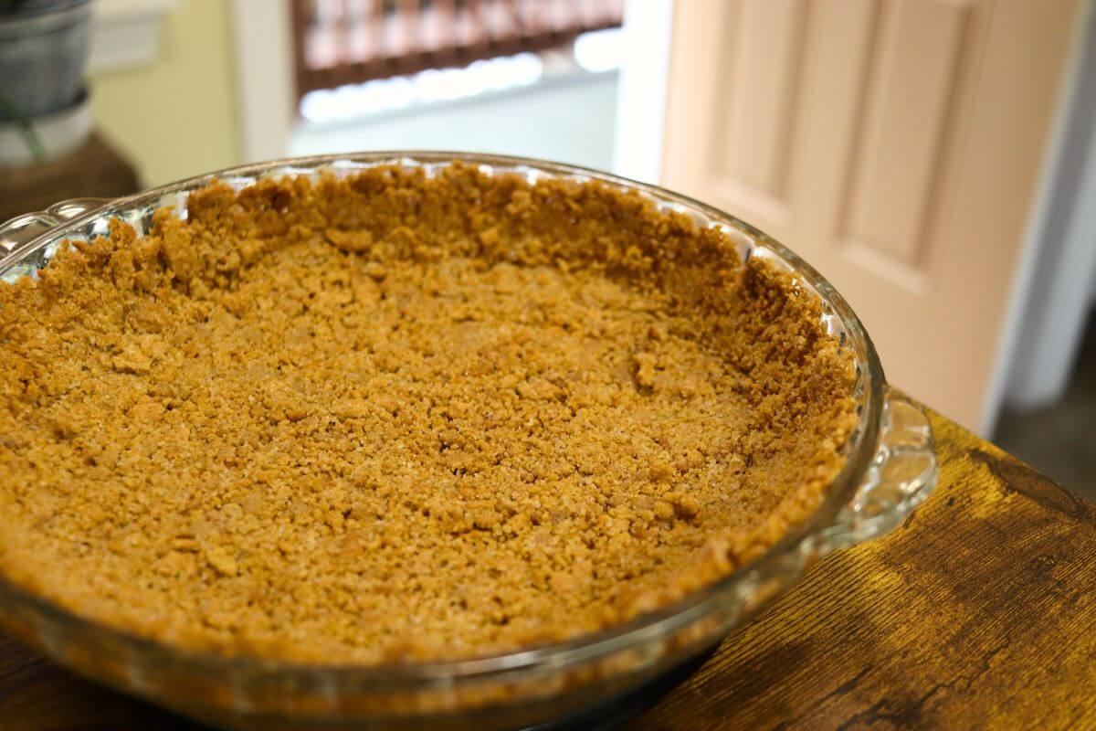 Homemade graham cracker crust with an even base and raised edges in a glass pie dish.