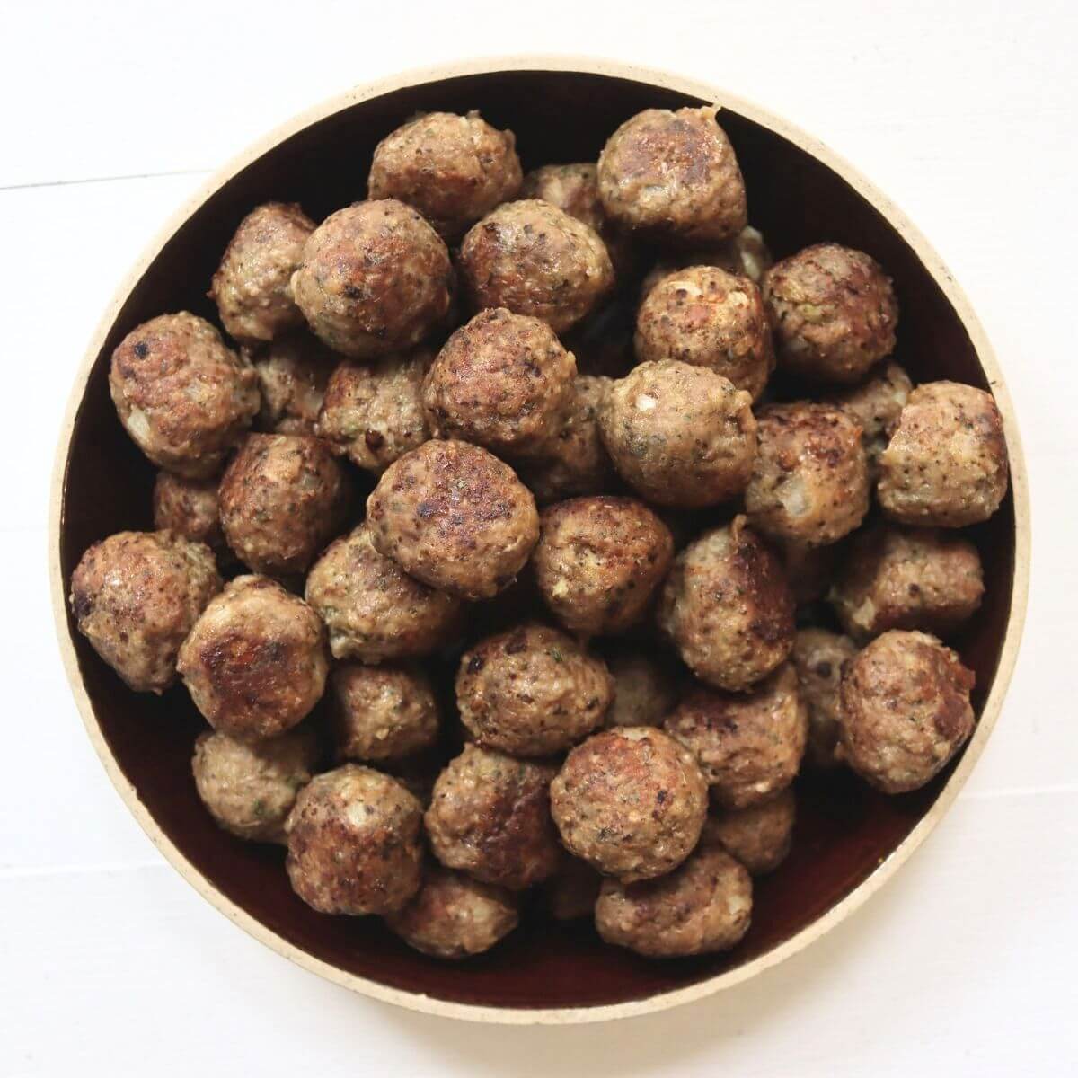 Mini turkey meatballs with golden-brown, pan-fried edges piled in a bowl.