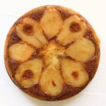 Pear upside down cake with eight golden pear slices arranged in a circular pattern over a glossy, caramelized brown sugar topping.