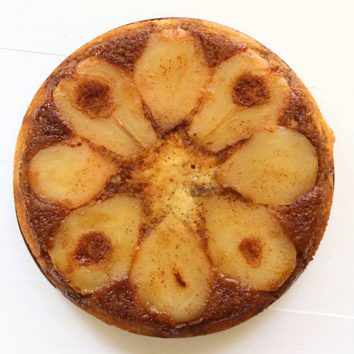 Pear upside down cake with eight golden pear slices arranged in a circular pattern over a glossy, caramelized brown sugar topping.