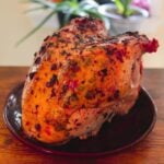 Oven roasted turkey breast with golden, buttery skin speckled with fresh herbs and dark roasted bits.