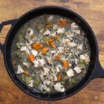 Turkey rice soup with chunks of tender turkey, wild rice, carrots, and celery in a black cast iron Dutch oven.